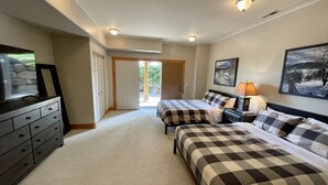 A bedroom with two beds, a dresser, a TV, and a door leading outside. - Stunnding Views in Every Room! 3 Full Bathrooms! (Kalispell)