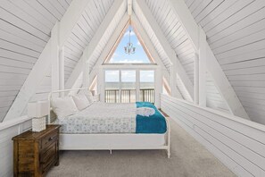 Un dormitorio con cama, mesita de noche y ventana con vista al mar.