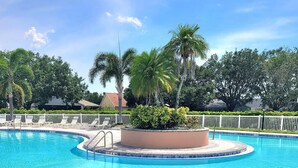 A clear blue pool with a circular deck, surrounded by palm trees and a white fence. - Townhouse •Pool •Air Hockey• Gated •Near Beach &IMG • 3 beds (Bradenton)