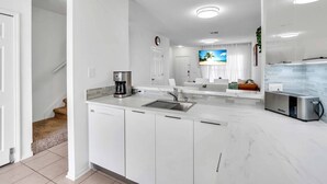 A modern kitchen with white cabinets, a coffee maker, and a built-in microwave. - Townhouse •Pool •Air Hockey• Gated •Near Beach &IMG • 3 beds (Bradenton)