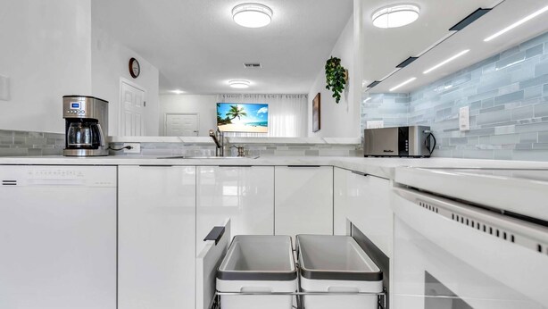 A modern kitchen with white cabinetry, a coffee maker, a microwave, and a large window with a beach view. - Townhouse •Pool •Air Hockey• Gated •Near Beach &IMG • 3 beds (Bradenton)
