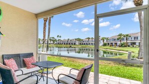 A patio with a table and chairs, a view of a lake, and a row of townhouses in the background. - Townhouse •Pool •Air Hockey• Gated •Near Beach &IMG • 3 beds (Bradenton)