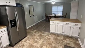 A kitchen with a refrigerator, cabinets, a dining table with chairs, and a window with blinds. - Cozy 3BR home close to trails. (Logan)