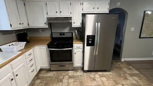 A kitchen with white cabinets, a stainless steel refrigerator, a built-in oven, and a microwave. - Cozy 3BR home close to trails. (Logan)