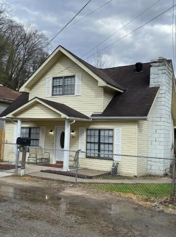A two-story house with a gabled roof, a front porch, and a brick chimney.