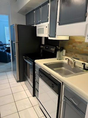 Enjoy cooking in this well-lit kitchen with a refrigerator, microwave, and sink.