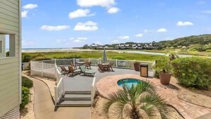 En terrasse med udendørs møbler, en swimmingpool og udsigt til strand og hav.