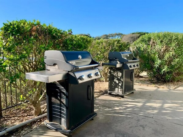 Two barbecue grills in an outdoor setting with a clear sky and greenery in the background. - Oceanfront Sands Beach Club 406, w/ Balcony + Beach Access! (Myrtle Beach)