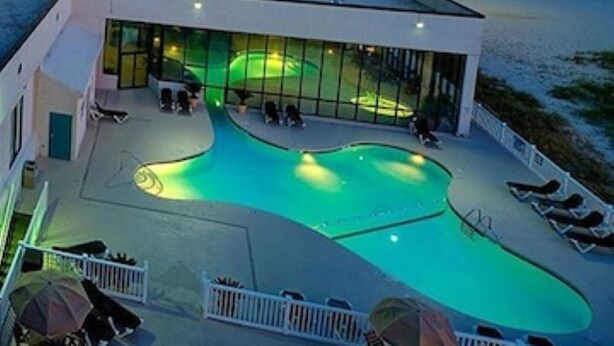En moderne bygning med swimmingpool, liggestole og et glashus.
