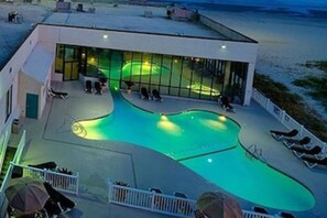 A modern building with a swimming pool, lounge chairs, and a glass enclosure. - Oceanfront Sands Beach Club 406, w/ Balcony + Beach Access! (Myrtle Beach)