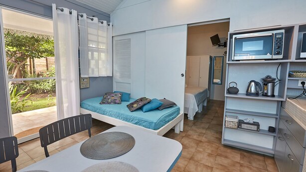 Una habitación pequeña con cama, un rincón de comedor y una kitchenette.