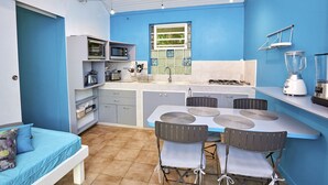 Cocina compacta con comedor, que incluye una mesa pequeña, sillas y electrodomésticos básicos.