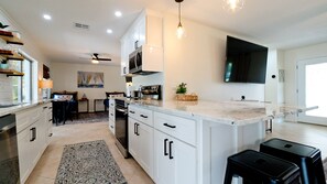 Une cuisine moderne avec des meubles blancs, un îlot central et un coin repas comprenant une table et des chaises.