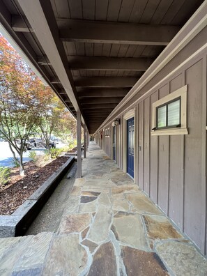 Guest rooms lead to a tranquil walkway lined with lush greenery and natural surroundings.