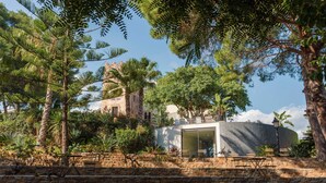 Paredes de pedra com área de estar ao ar livre e um edifício com fachada de vidro.