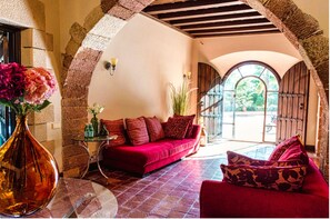 Relax in this inviting space with a sofa under an arched ceiling, a glass table, and a potted plant.