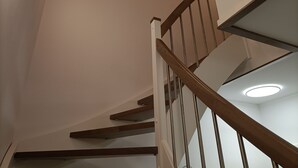 Una escalera con barandales de madera y una pared blanca.