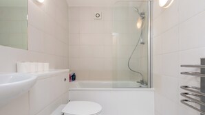 Un baño moderno con cabina de ducha de vidrio, inodoro blanco y lavamanos con espejo.
