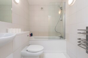 Een moderne badkamer met een douchecabine van glas, een wit toilet en een wastafel met spiegel.