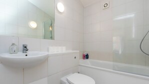 Un baño con lavamanos, espejo, inodoro y ducha.