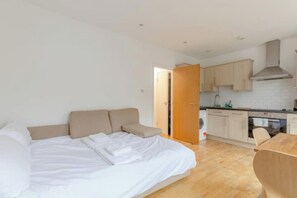 Un dormitorio con cama, sofá y mesa de comedor de madera.