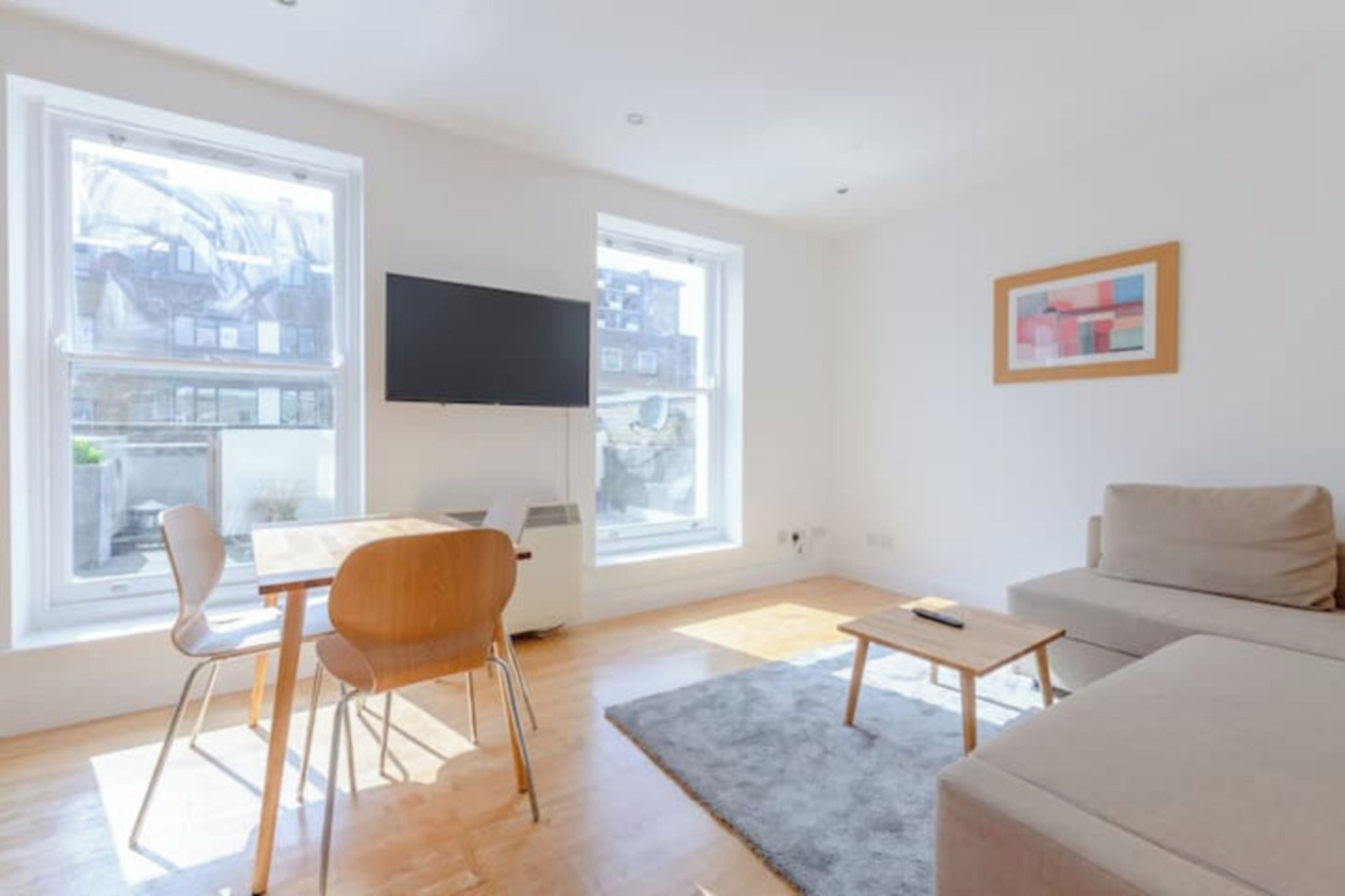 En moderne stue med sofa, sofabord, fjernsyn og en lænestol.