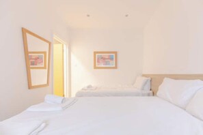 Une chambre d’hôtel avec deux lits, un grand miroir et un tableau encadré au mur.