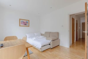 Un dormitorio con una cama, un escritorio y una silla. Hay una puerta que da a otra habitación.