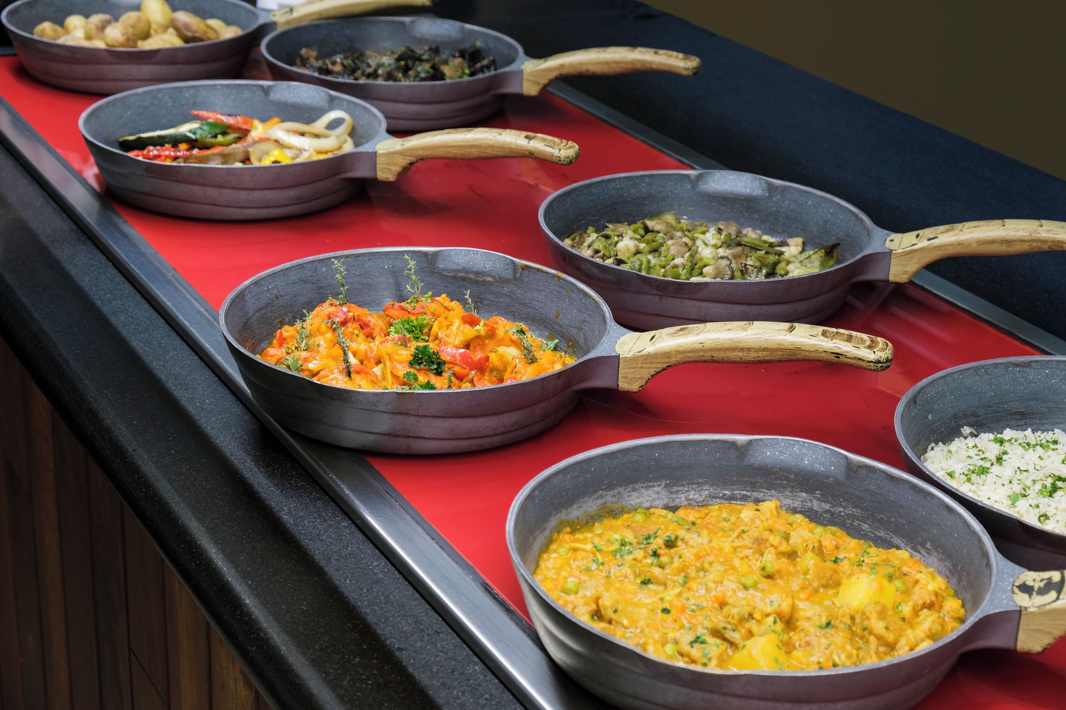 Un buffet proposant divers plats servis dans des plats en métal, notamment un plat de riz et un autre contenant un plat jaune.