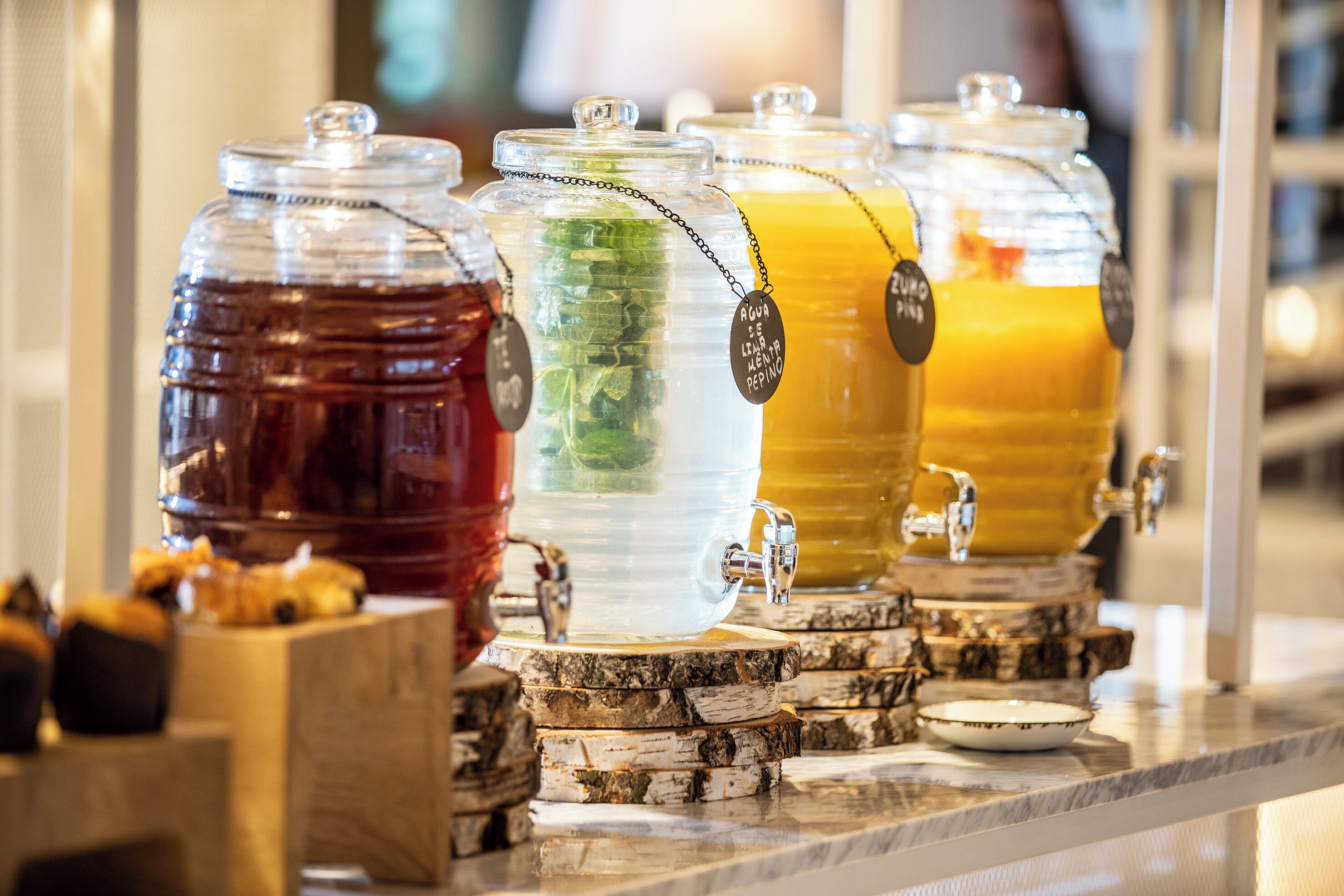 Una estación de bebidas con varios dispensadores, cada uno identificado con una bebida distinta.