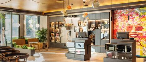 A modern hotel lobby with seating areas, a reception desk, and a large floral mural.