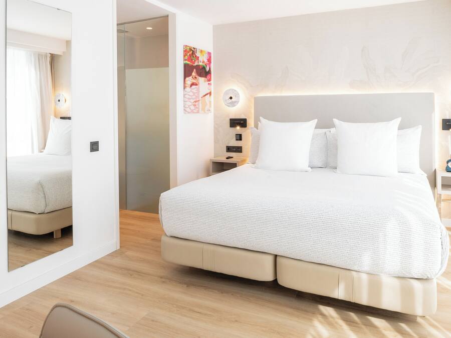 Ein modernes Hotelzimmer mit einem großen Bett, Nachttischen, einem Spiegel und einem Wandbild.