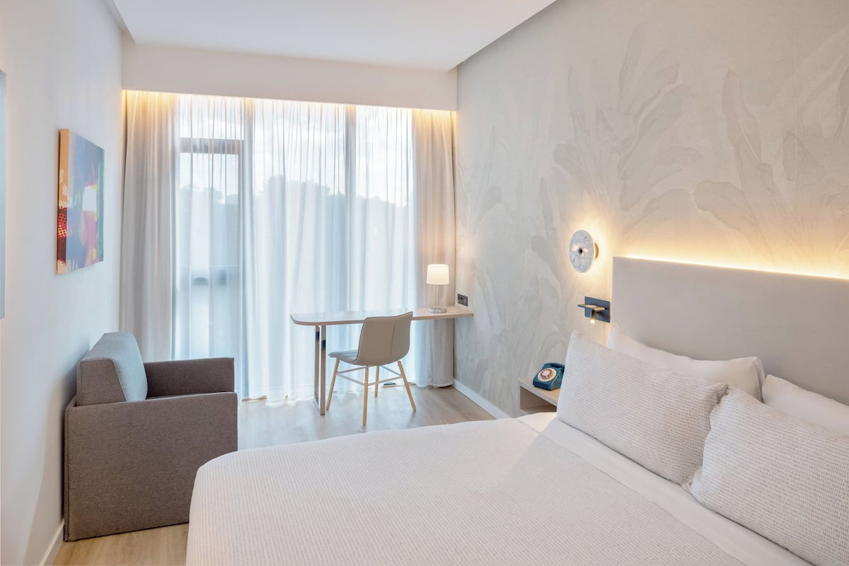 Ein modernes Hotelzimmer mit einem großen Bett, einem Schreibtisch und einem Stuhl.