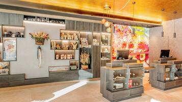A modern interior with wooden shelves displaying various items, a large floral artwork on the wall, and a warm ceiling design.