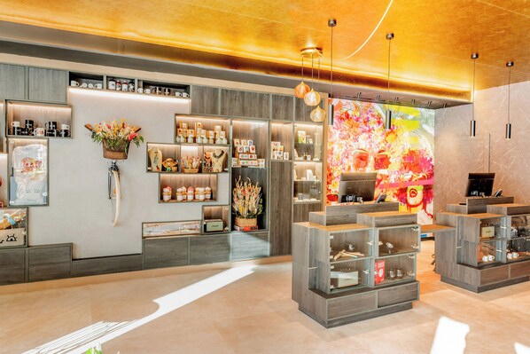Un interior moderno con estanterías de madera que exhiben diversos objetos, una gran obra de arte floral en la pared y un diseño de techo cálido.