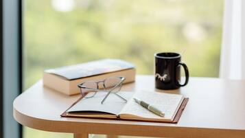 A table with a book, glasses, a pen, and a mug.