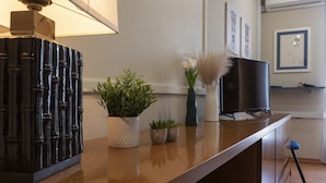 Una encimera de cocina con un objeto decorativo negro, una planta en maceta y un jarrón con flores blancas.
