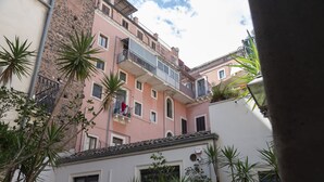 Un edificio de varios pisos con balcones, una puerta y plantas en macetas.