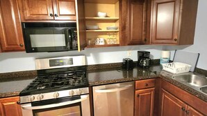 A kitchen with wooden cabinets, a stainless steel stove, a microwave, and a dishwasher. - Cozy Treasure Home with private entrance (Buford)