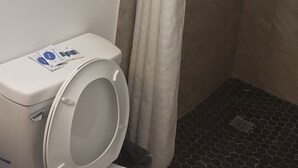 Une salle de bain comprenant des toilettes, une douche avec un rideau et un porte-serviettes avec des serviettes.