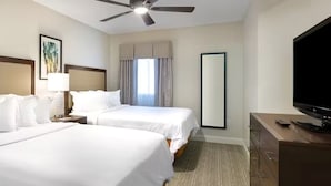 Une chambre d’hôtel avec deux lits, un ventilateur de plafond, une télévision et un grand miroir.