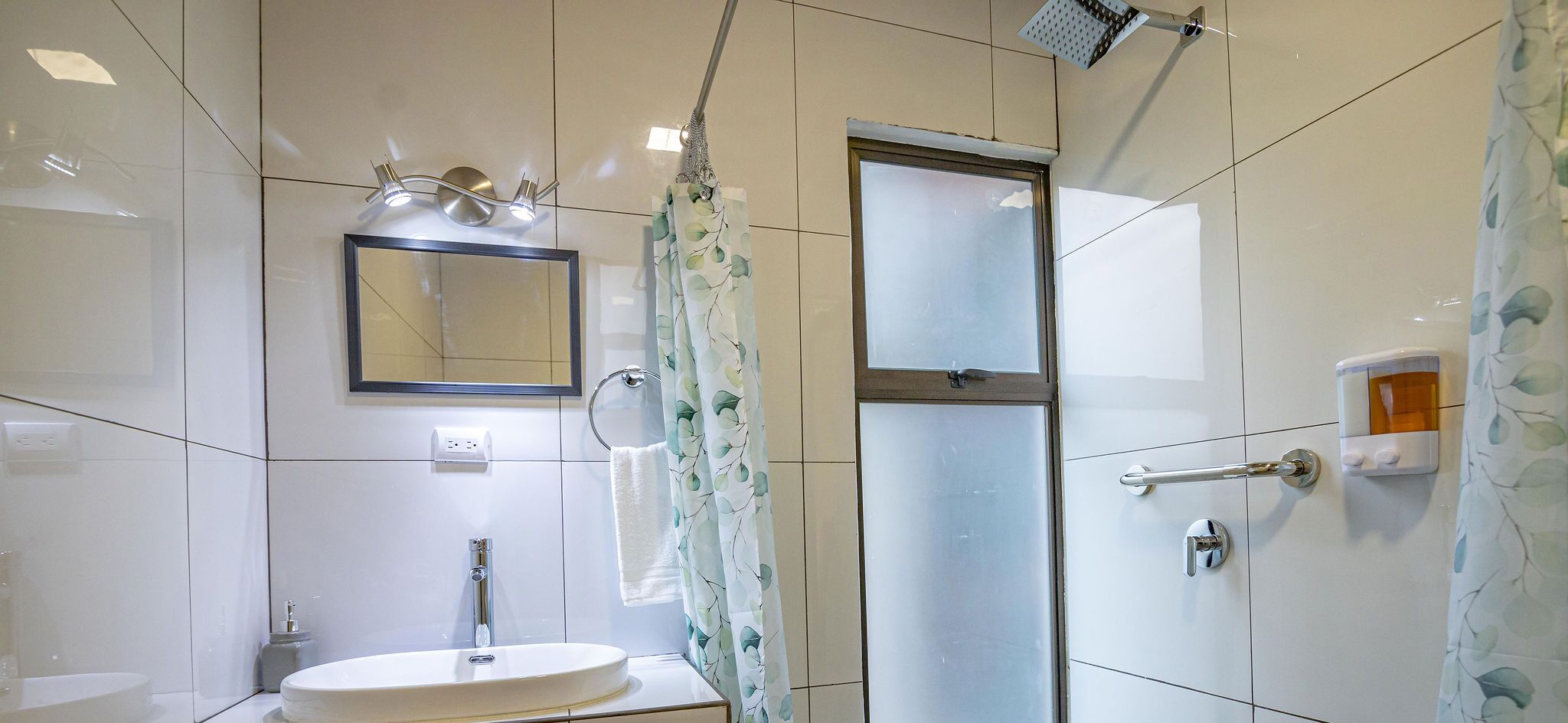A bathroom with a sink, mirror, shower, and a glass door.