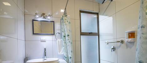 A bathroom with a sink, mirror, shower, and a glass door.