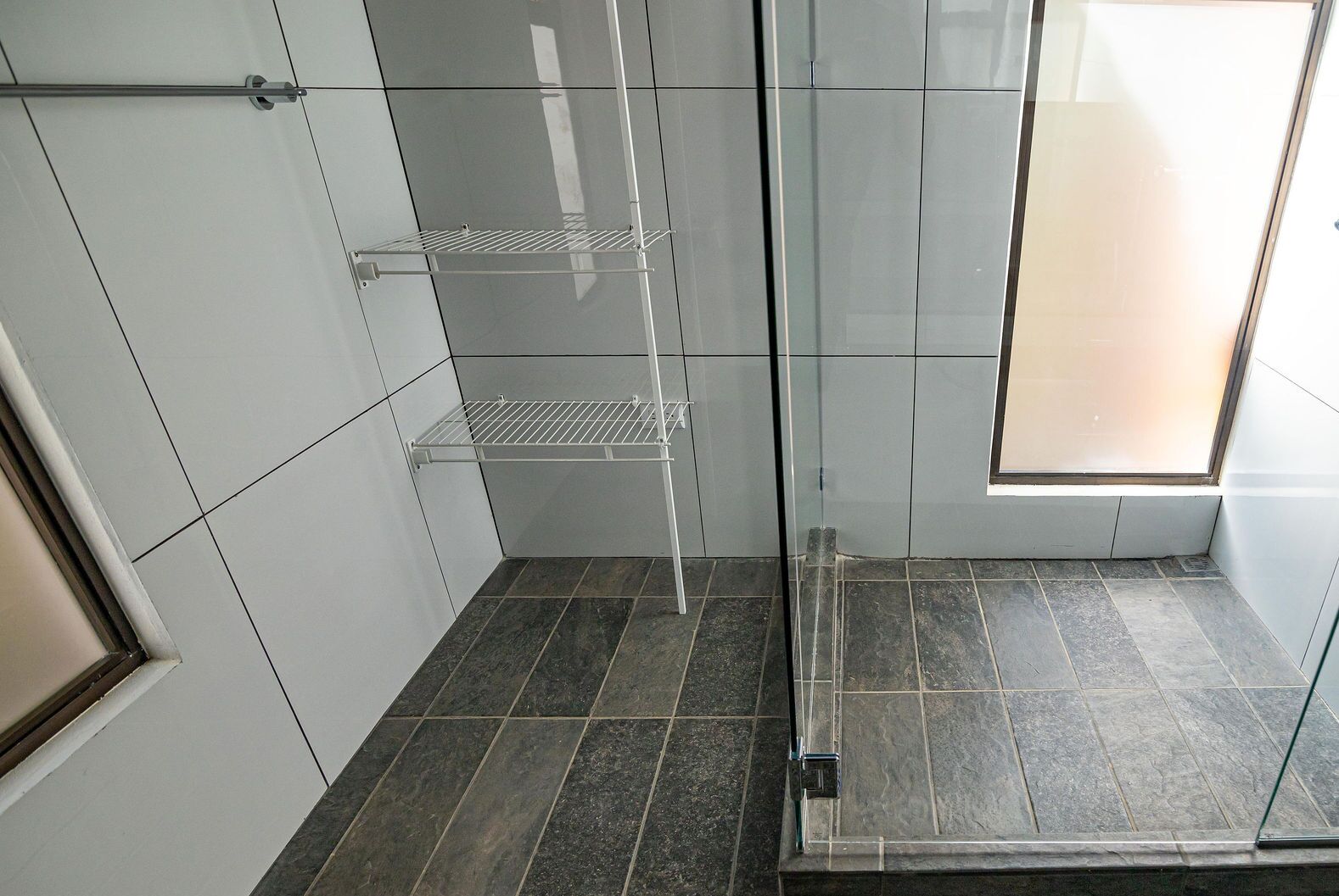 A bathroom with a shower area, tiled walls, and a window.