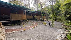 A resort with wooden cabins, a gravel pathway, and surrounding greenery. - Riverside Bungalows (Quepos)