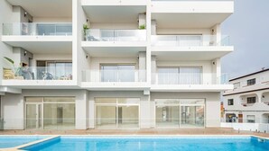Een meerlaags gebouw met balkons, een zwembad en glazen deuren.