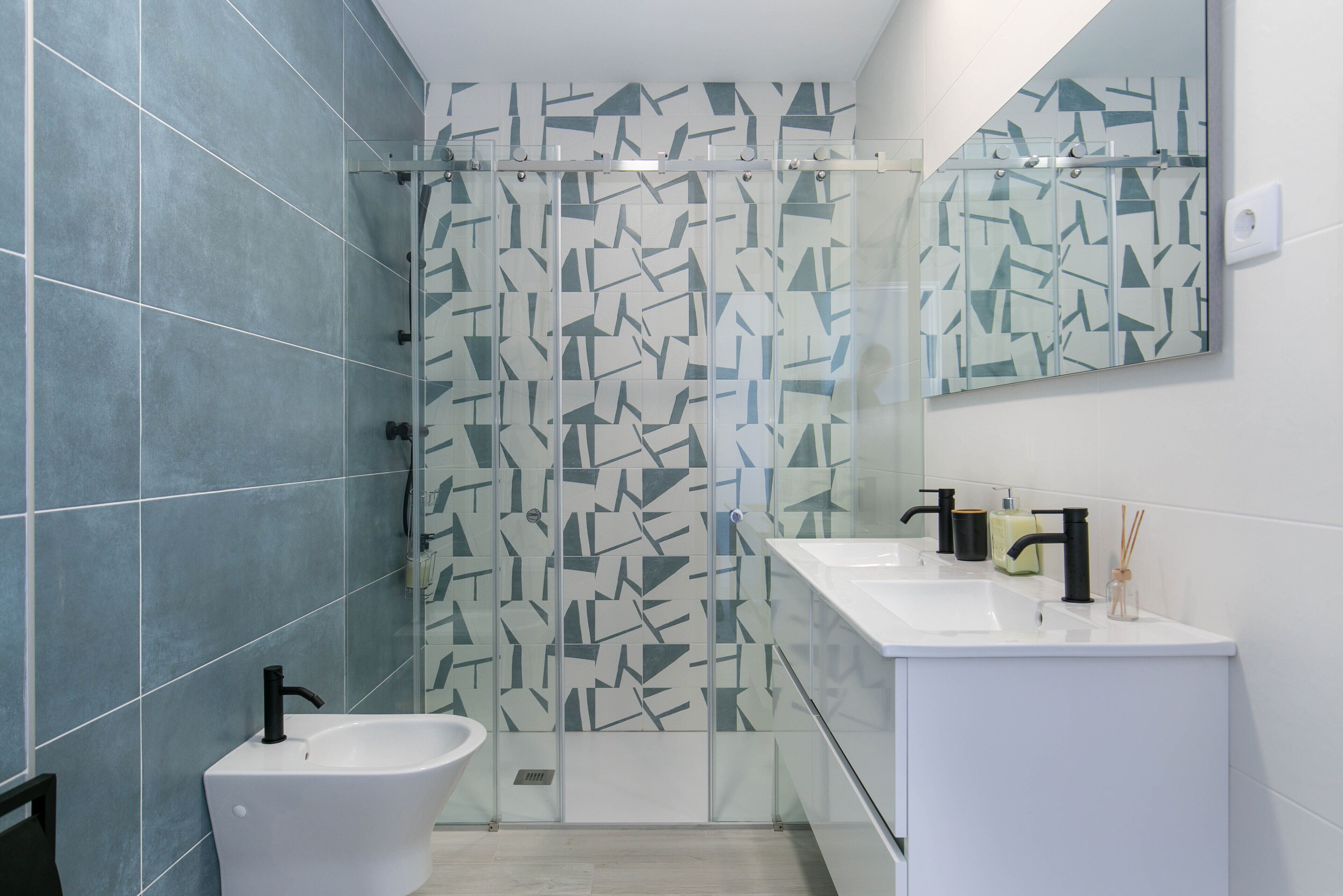 Ein modernes Badezimmer mit einer freistehenden Badewanne, einer Duschkabine aus Glas und einem weißen Waschtisch mit Spiegel.