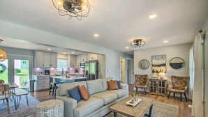A spacious living area with a sofa, coffee table, and chairs, a kitchen with modern appliances, and a dining area with a table and chairs. - True Lakefront, Easy Water Access, Dock, Hot Tub, Sleeps 12 (Penhook)