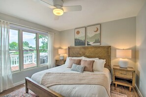 Ein Schlafzimmer mit einem großen Bett, zwei Nachttischen mit Lampen, einem Deckenventilator und einem Kunstwerk an der Wand.