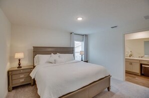 Cozy retreat with a large bed, nightstand, and bathroom featuring a mirror and sink.